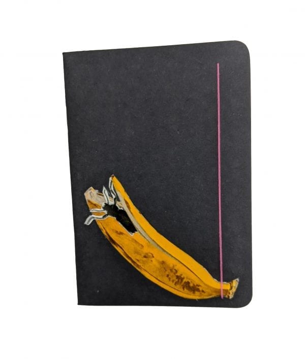 Embroidery art on small black notebook, collage of bug climbing out of banana