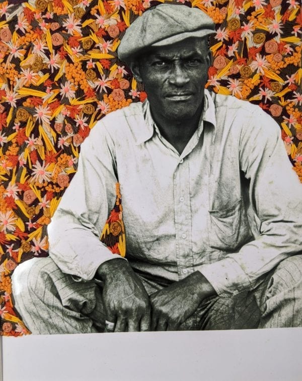 Embroidery art of orange flowers on black and white photo of man sitting on steps